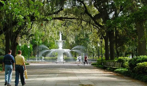 people walking a park with a fountain in the middle