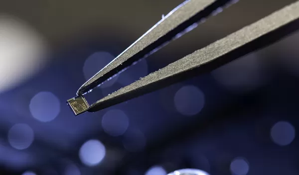 Closeup of tweezers holding a tiny chip.
