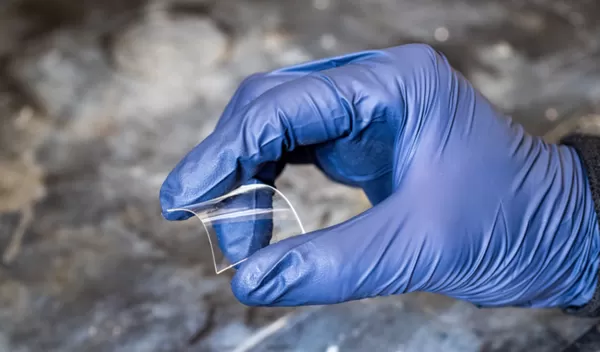 gloved hand holding bent plastic