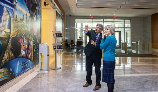 Panch standing in front of NSF art wall explaining the details to a staff member