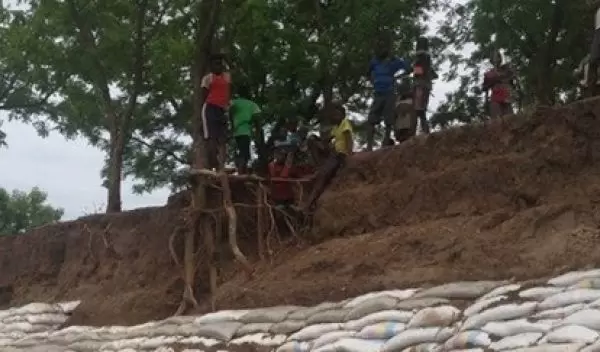 Children in Malawi standing above a flood barrier