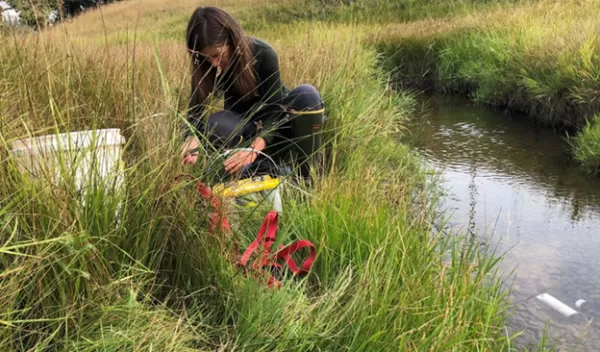 Joanna Blaszczak by a stream setting up sensors