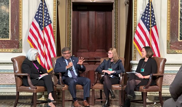 White House Office of Science and Technology Policy Director Arati Prabhakar, NSF Director Sethuraman Panchanathan, NIST Director Laurie Locascio, and ARPA-H Director Renee Wegrzyn sit in together in armchairs between two American flags.