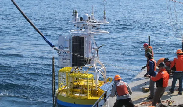 Workers on a ship releasing a scientific buoy into the ocean