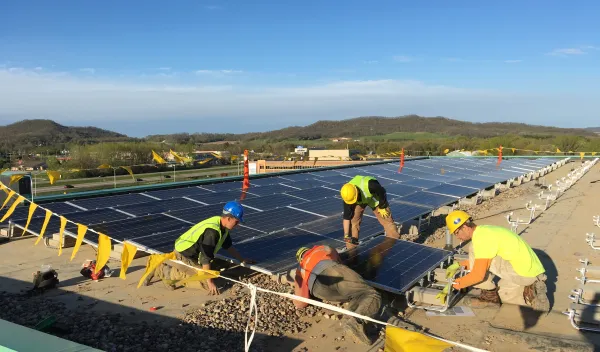 Madison College graduate Mike Reuter (in blue helmet) leads a solar panel installation crew for a renewable energy program