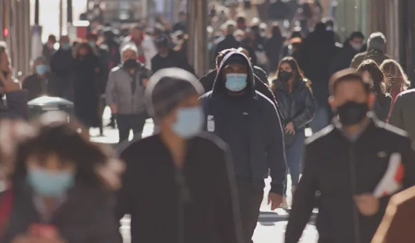 People walking on a city sidewalk wearing masks during the coronavirus epidemic.