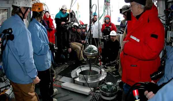 A group of people in coats around some equipment.