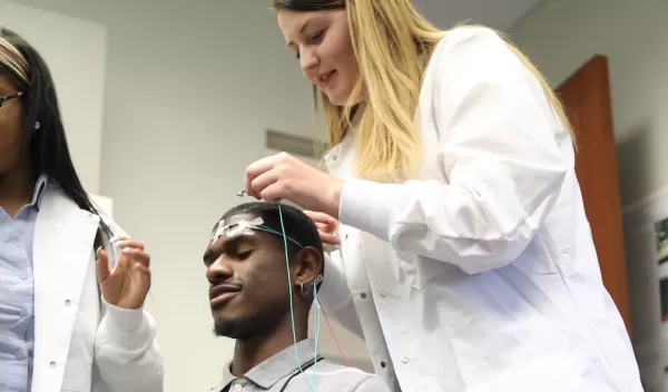Two students place electrodes on a research subject's head.