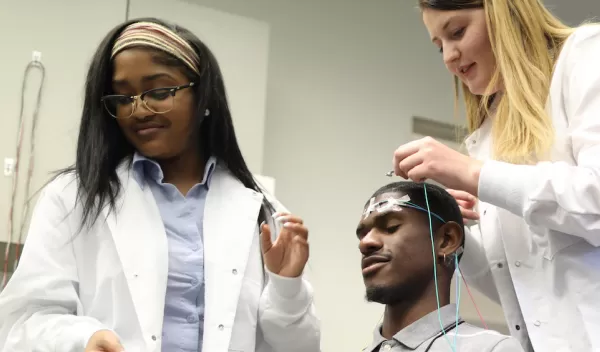 Two students place electrodes on a research subject's head.