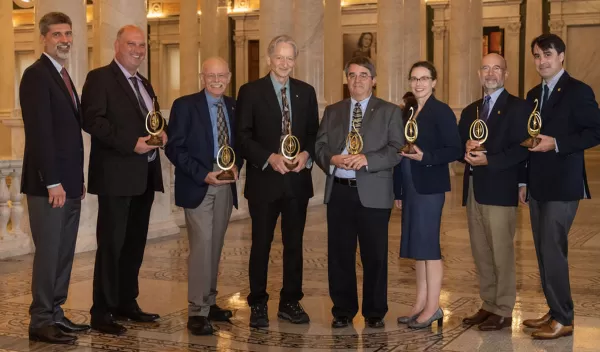a group of 8 people that received awards wearing suits