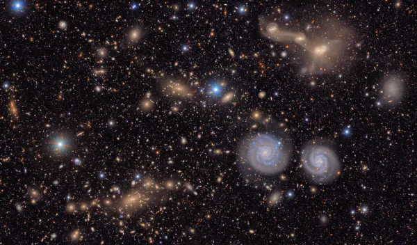 Many stars and galaxies including two spiral galaxies and three merging galaxies.