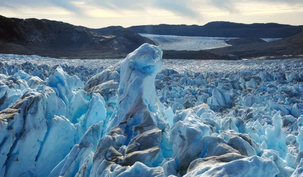 Blue and white spikes of ice in the foreground with rocks and glacier in the background.