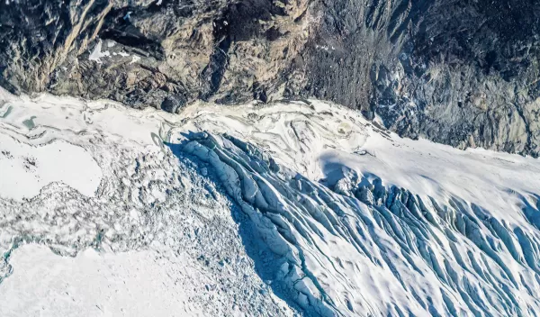 An aerial view of where bedrock, sea ice, a glacial river, crevasses, and icebergs meet. Western Greenland Ice Sheet.
