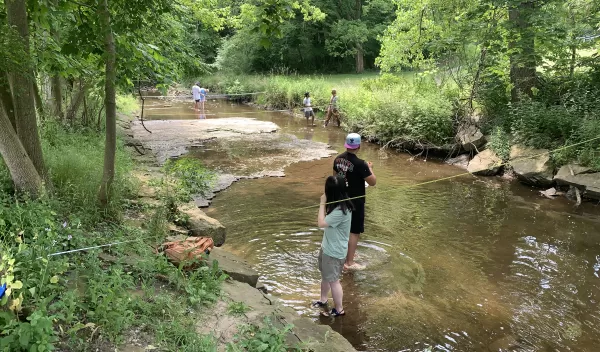 people standing in a body of shallow water fishing