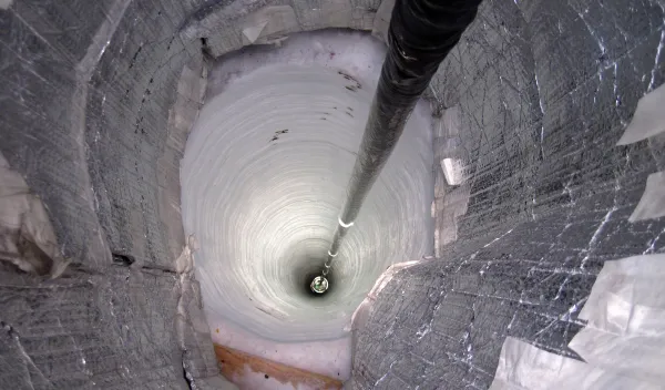 A long tube extending into a hole in ice.