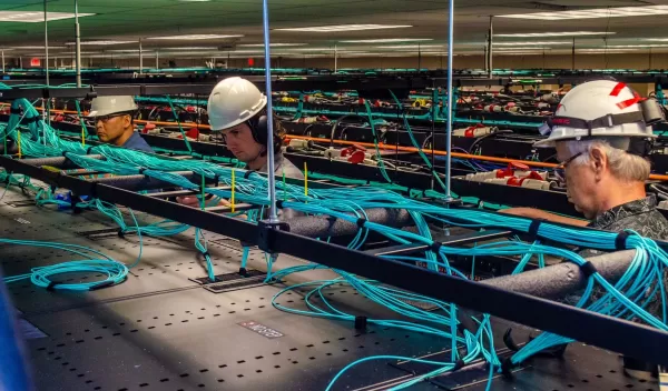 employees work on the network cabling above the racks of Frontera.