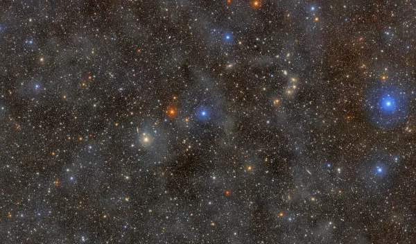 A dense field of colorful stars shining through a dust cloud