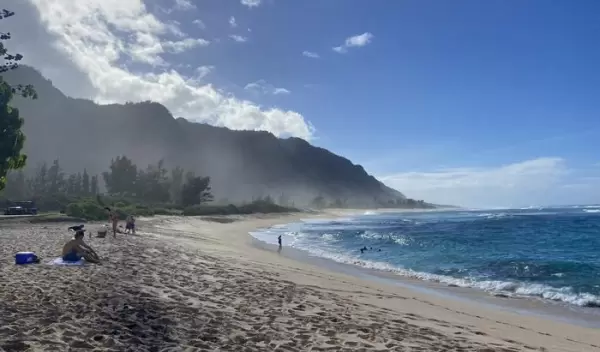 ocean and mountain landscape with people sitting on the beach