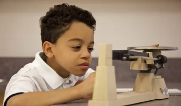 Student in science class with balance.