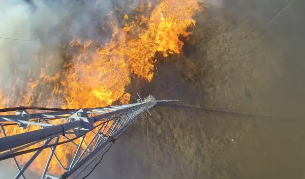 An experimental grass fire spreads under a meteorological tower.