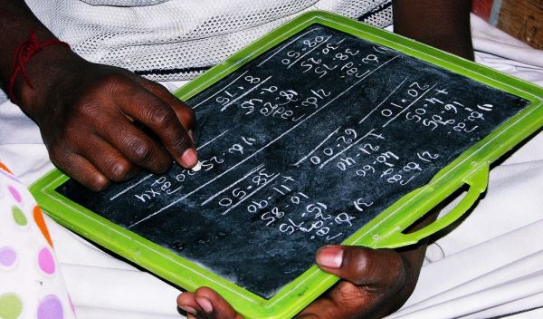 hands of a girl doing math problems on slate