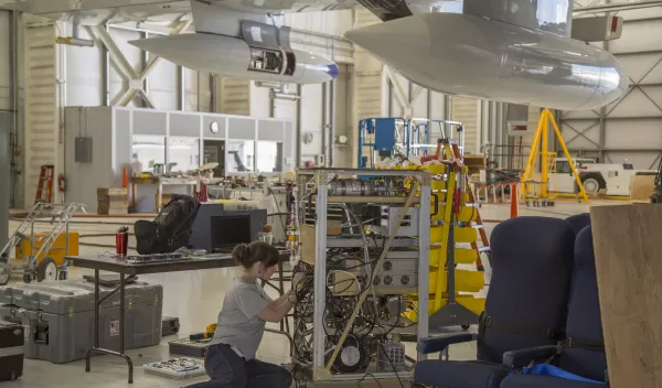 woman working in a facility to  mount air-sampling instruments on airplane