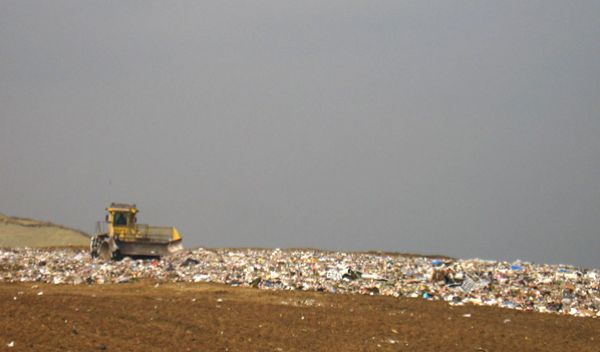 A piece of heavy equipment pushes trash in a landfill.