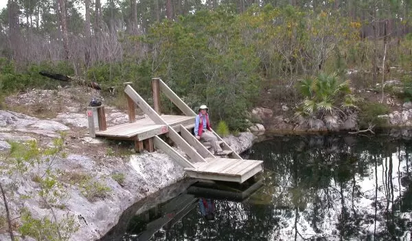 person sitting next to a lake formed in a flooded sinkhole