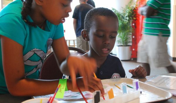 Young museum visitors use a paint set of acids and bases to learn about pH.