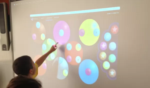 student pointing at a planet on a projected display
