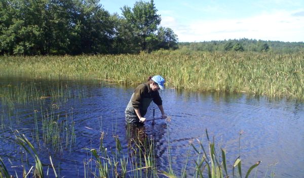 Scientist in lake collecting sediment samples in Maine