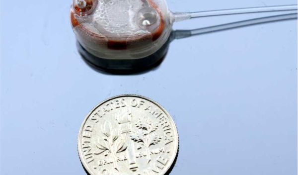 implantable infusion micropump next to a dime for size comparison