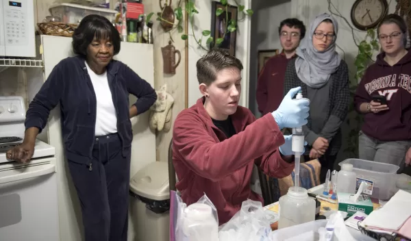 researchers test water in a kitchen while the resident is watching