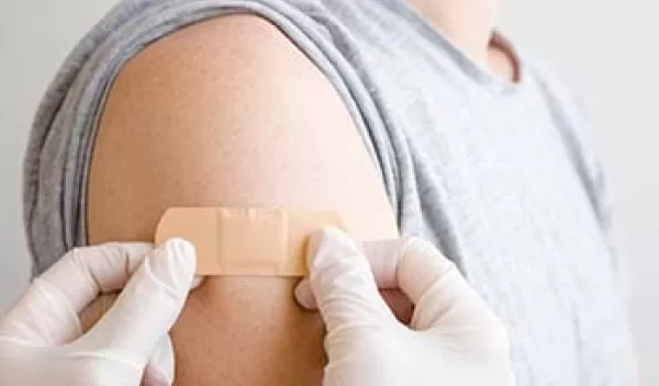 doctor putting adhesive bandage on young man's arm