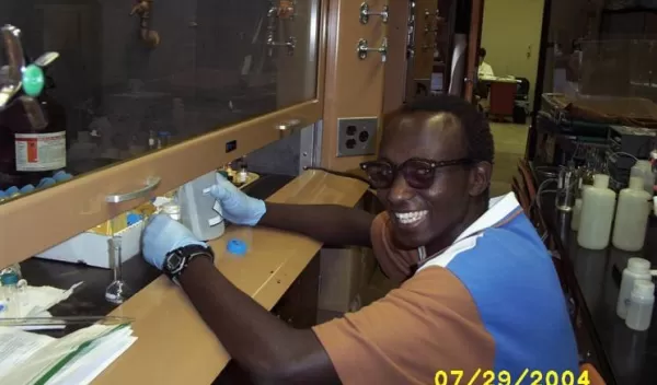 student works with lab equipment under hood