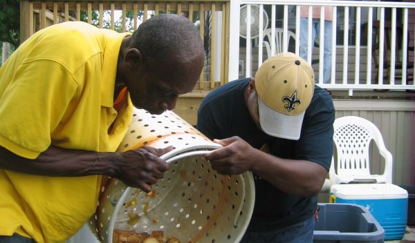 Two men dumping shrimp and corn from a food basket