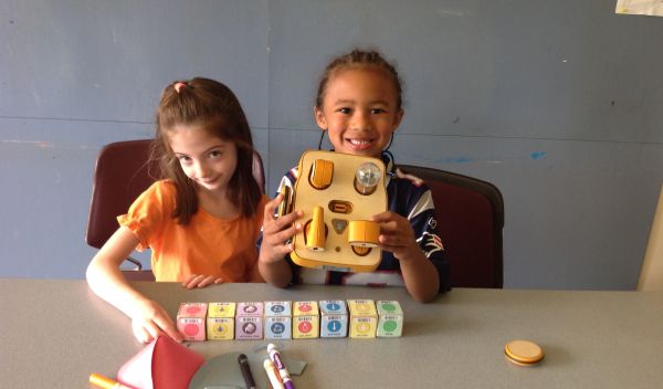 two girls with crayons, a robot and cubes