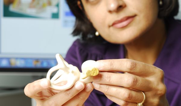 Pamela Bhati holding a cochlear implant