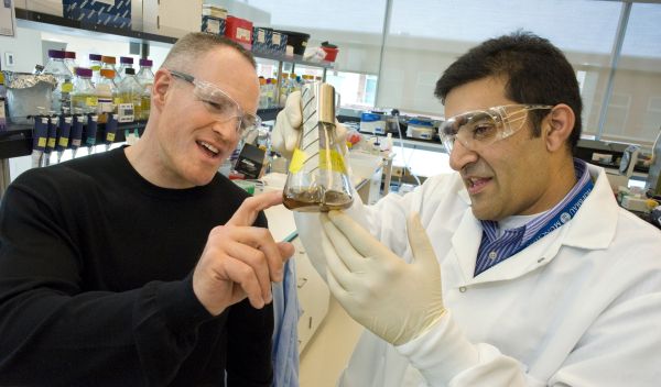 Photo of JBEI Director Jay Keasling with Rajit Sapar in lab with a beaker of cellulose sludge.