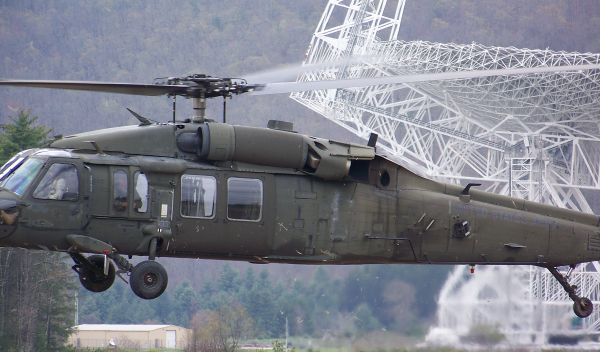 Photo of a Blackhawk helicopter lifting off in front of the Robert C. Byrd Green Bank Telescope.