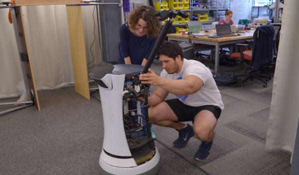 Two students add a manipulating arm to a robot base
