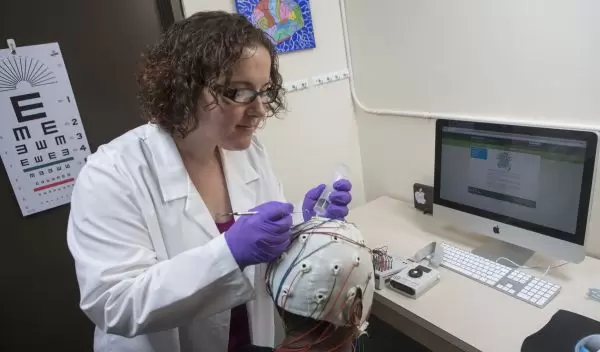 Sarah Laszlo prepares a subject to measure brain activity using electroencephalography (EEG).