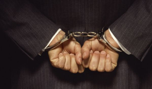 Photo of a man's hands cuffed behind his back.