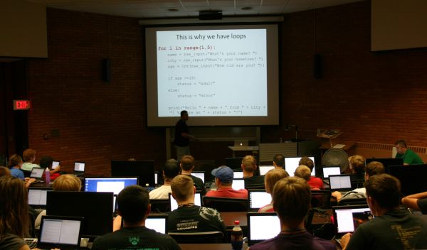 students in an auditorium looking projector screen
