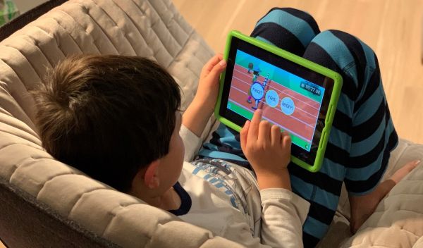 little boy sitting on a sofa playing with a tablet