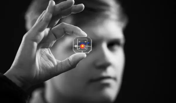 Rachel Young, a graduate student, holds up the new eye-on-a-chip device