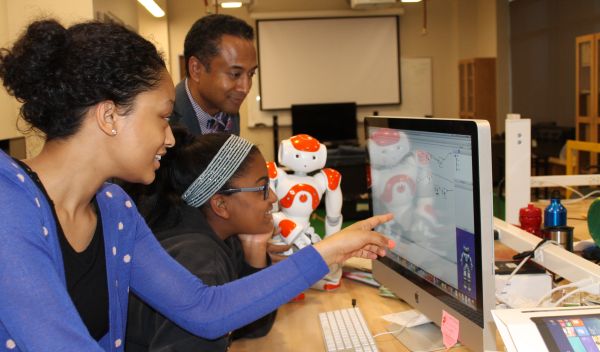Photo of Andrew Williams instructing girls using the Choreographe visual programming environment