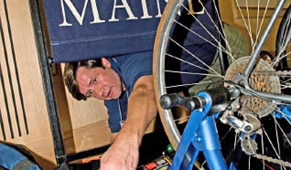 Photo of a man connecting a bicycle to a series of cables.