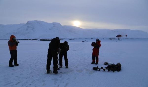 an ice auger is used to drill a borehole through Isortoq River