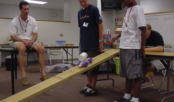 Students watch as robot rolls down plank.